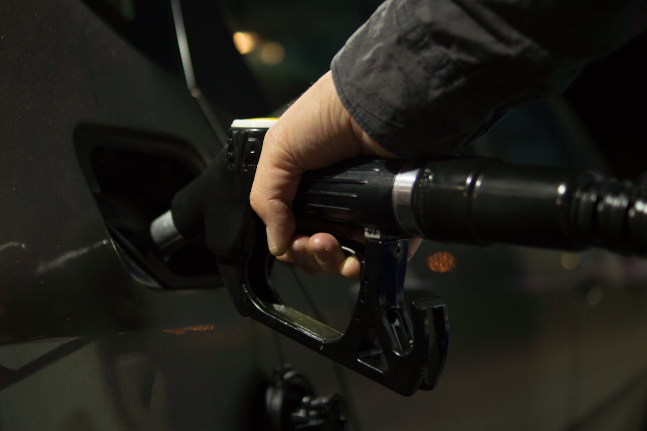 about-us Close-up of a person refueling a car at a gas pump during night.